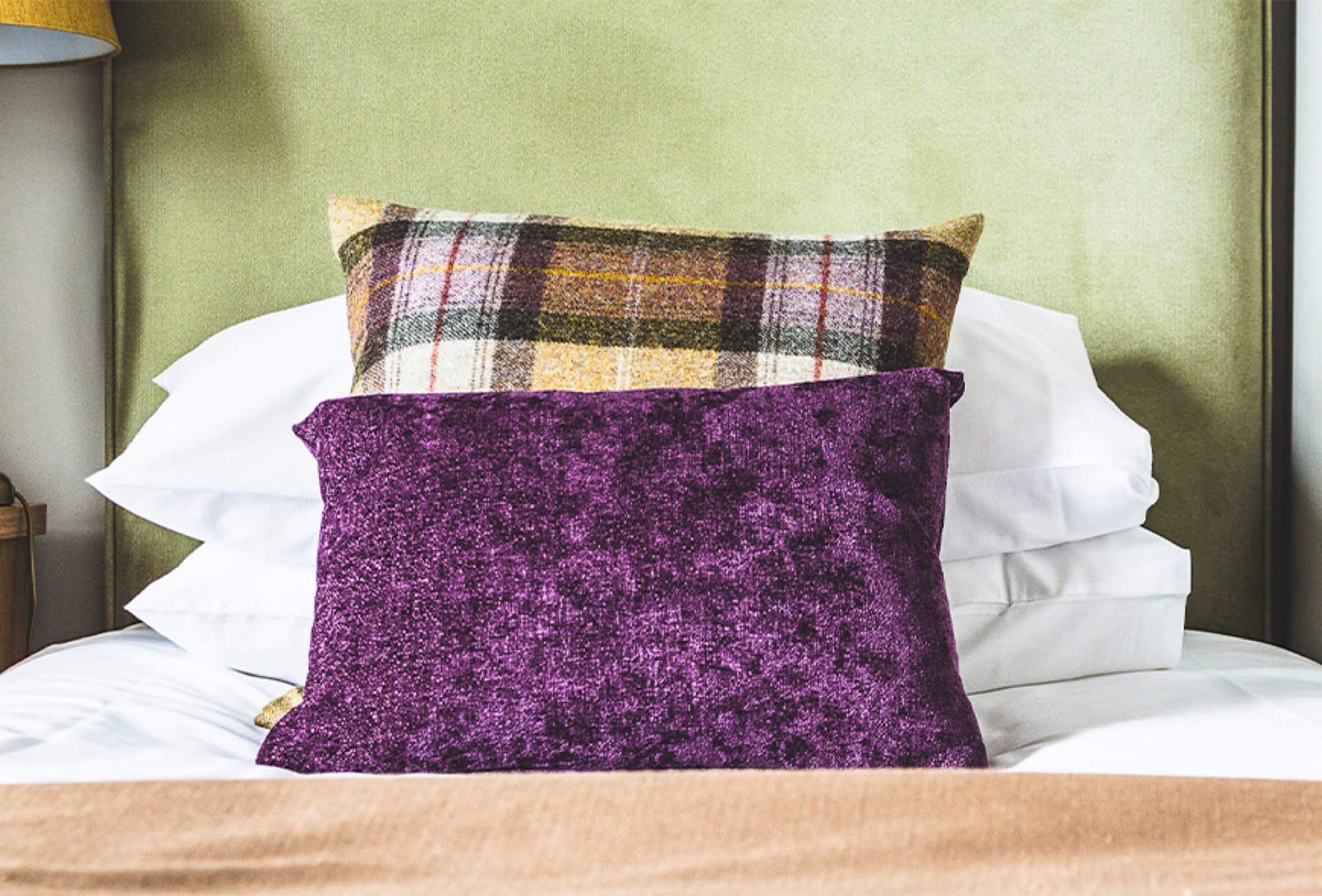 Des coussins en tweed et en velours sur le lit